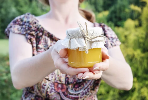 Woman holds a glass jar of honey. — Stock Photo, Image