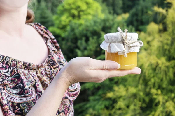 Woman holds a glass jar of honey. — ストック写真