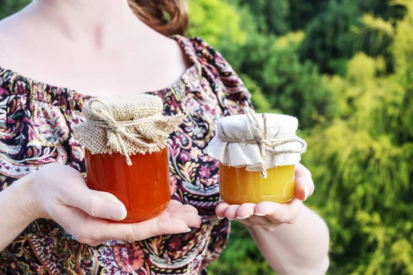 Woman holds two glass jars of honey. — Stock Photo, Image