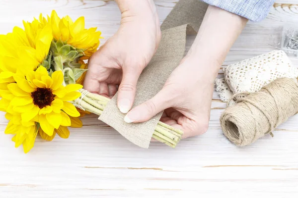 Frau zeigt, wie man Strauß mit Sonnenblumen macht — Stockfoto
