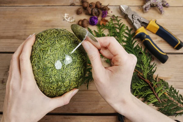 Woman shows how to make Christmas ball with styrofoam sphere and — Stock Photo, Image