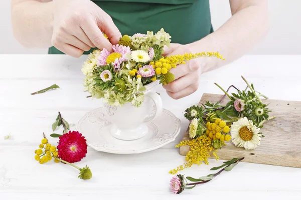 Žena ukazuje, jak udělat květinové aranžmá s letními květinami i — Stock fotografie