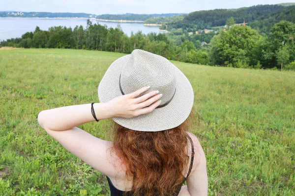 Jonge vrouw met een vakantiehoed kijkt naar het prachtige landschap. — Stockfoto