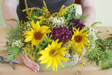 Kadınlar ayçiçekleriyle nasıl çiçek aranjmanı yapılacağını gösterirler.