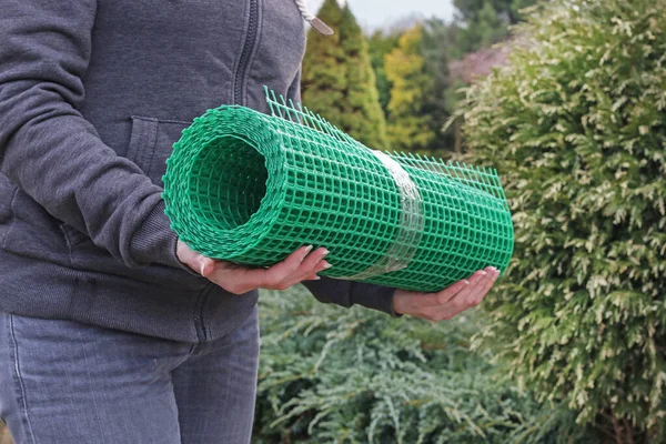 Ein Mann hält ein Plastiknetz in der Hand, das bei der Gartenarbeit nützlich ist. — Stockfoto