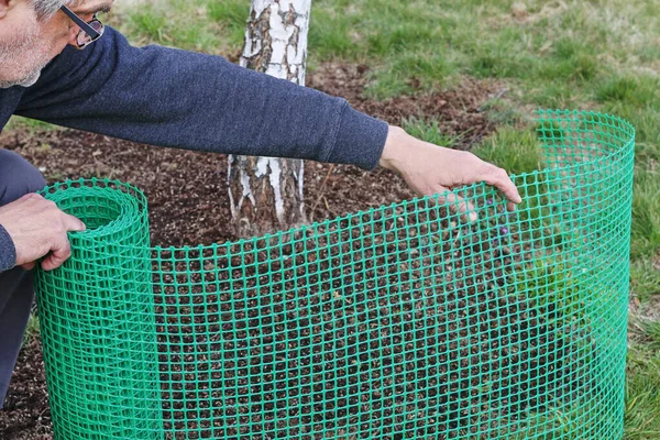 Mężczyzna posiada plastikową siatkę, która jest przydatna w ogrodnictwie. — Zdjęcie stockowe