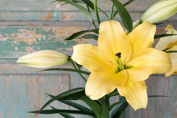 Yellow lily flowers on green wooden background. — Stock Photo, Image