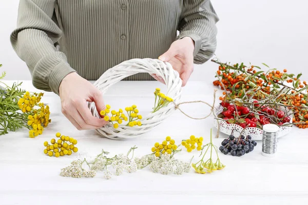 Woman shows how to make autumn wreath with rose hip, tansy and s — Stock Photo, Image