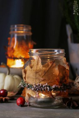 Renkli yapraklar ve fundalarla süslenmiş sonbahar feneri kavanozları.