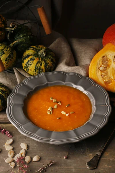 Pumpkin creamy soup in ceramic plate on wooden table. — Stock Photo, Image