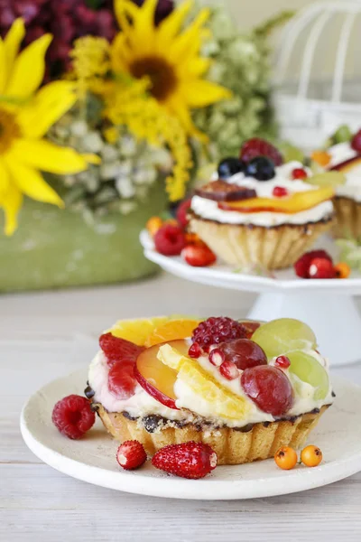 Schöne Cupcakes mit frischen Früchten dekoriert: Trauben, Pfirsich, o — Stockfoto