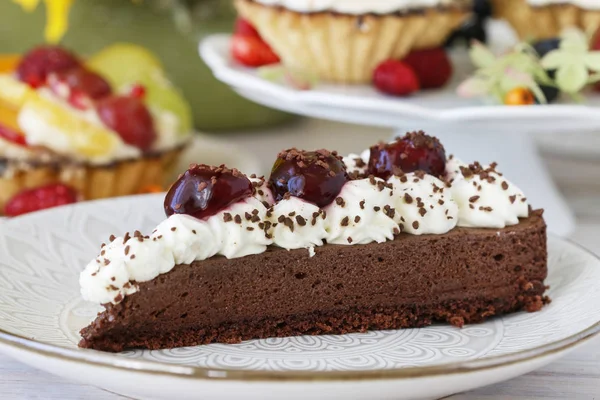 Pastel de chocolate con crema batida decorado con cerezas en un s —  Fotos de Stock