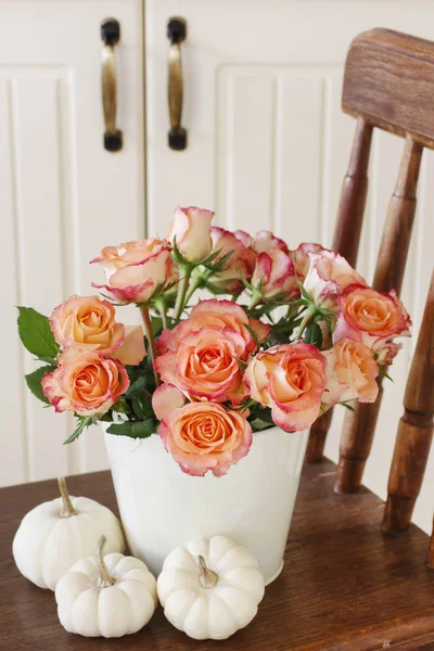 Beautiful roses in white decorative bucket and baby boo pumpkins