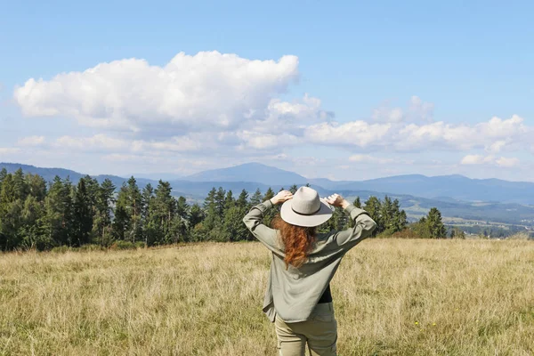 Jonge vrouw met een vakantiehoed kijkt naar het prachtige landschap. — Stockfoto