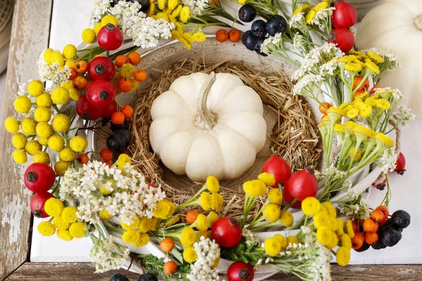 Herbstkranz mit Hagebutte, Stiefmütterchen und Spiraea auf weißem Holz — Stockfoto