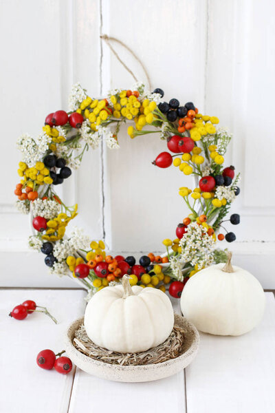 Осенний венок с шиповником, тэнси и спиреей на белом деревянном b
