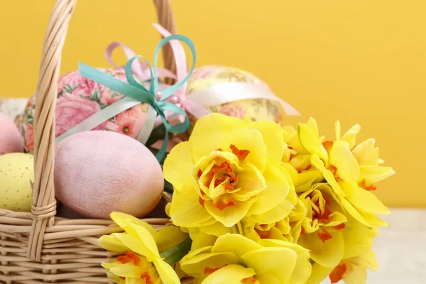 Wicker korg med påskägg och bukett av påsklilja blommor. — Stockfoto