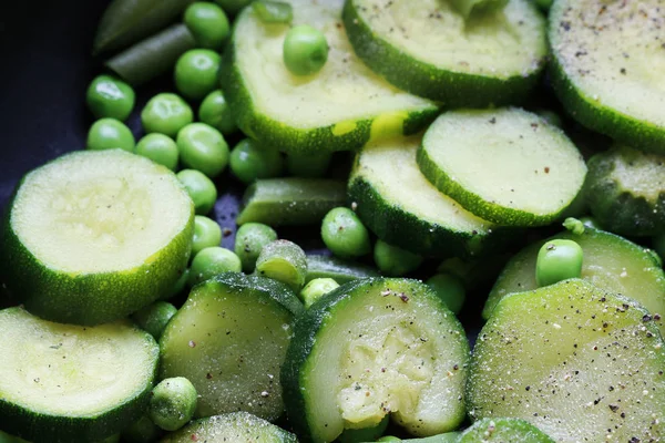 Зеленый горох и кусочки цуккини, приготовленные для жарки на сковороде . — стоковое фото