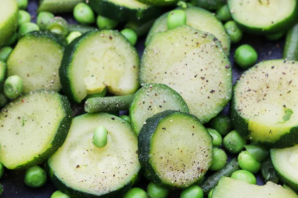 Guisantes verdes y rodajas de calabacín preparados para freír en una sartén . — Foto de Stock