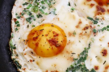 Consecutive steps of preparing fried eggs with ham and herbs