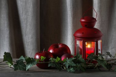 Christmas decoration with red lantern, candle, apples and ivy le