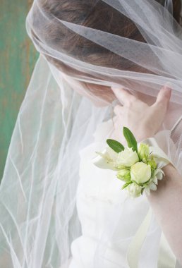 Gelin gül ve eustoma çiçekyapılmış bilek korsaj giyiyor. Parti dekoru