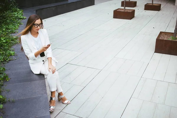 Joven mujer de negocios atractiva con el pelo largo está utilizando el teléfono inteligente sobre un fondo gris con área de espacio de copia para su texto o diseño . — Foto de Stock