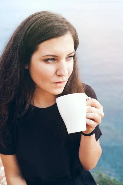 Joven mujer atractiva bebe café y disfruta de los frescos de la mañana y la luz del sol suave — Foto de Stock