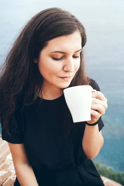 Mujer joven bebe té y disfruta de los refrescos de la mañana y la luz del sol suave — Foto de Stock