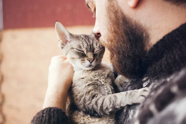 Close-up de belo jovem que está de pé em uma varanda com seu gato . — Fotografia de Stock