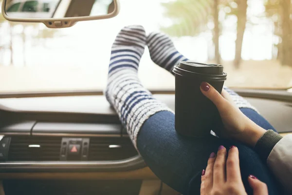 Mujer pies en largos calcetines calientes divertidos en el tablero de instrumentos del coche . — Foto de Stock