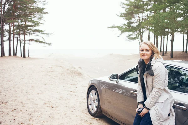 Feliz joven mujer está de pie junto al coche, relajarse después de un largo viaje de aventura por carretera . — Foto de Stock