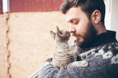 Yakın çekim kedi onun ile bir Balkonda duran genç bir adam. Ev evcil hayvan.