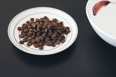 Kediler için Kuru gıda koyu ahşap zemin üzerinde beyaz plaka. 