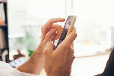 Korona virüsü karantinasında kalırken cep telefonu kullanan erkeklerin el kameralarını kapatın. Arkadaşlarla ve ailelerle sohbet etmek, son haberleri okumak ve internette güncellemeler yapmak..