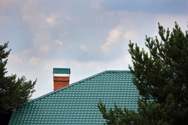 Cheminée en brique sur le toit en métal vert — Photo