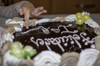 Doğum günü, bir çocuğun eli parmaklarıyla pastayı tadıyor