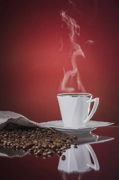 Uma xícara de café quente fumegante no fundo vermelho gradiente — Fotografia de Stock