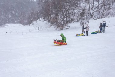 Maikop Adigeya Bölgesi, Rusya Federasyonu, 01.04.2019: Dağlarda kış tatili, farklı spor, aile eğlencesi, karlı ve bulutlu hava, yumuşak odak, metin için bir yer.