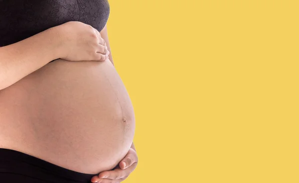 Η κοιλιά Ασίας έγκυος γυναίκα με Primrose pantone χρώμα φόντου — Φωτογραφία Αρχείου