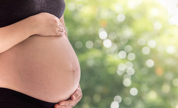 Εσωτερικη η κοιλιά Ασίας έγκυος γυναίκα με το πράσινο της φύσης θάμπωμα του φόντου — Φωτογραφία Αρχείου