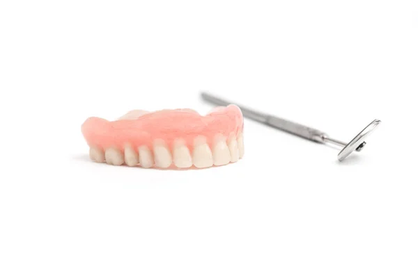 Prótesis dentales superiores y espejo dental sobre fondo blanco — Foto de Stock
