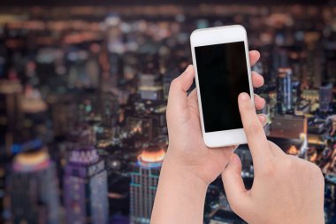 Bir telefon bulanık gece iş şehir arka planda tutarak el