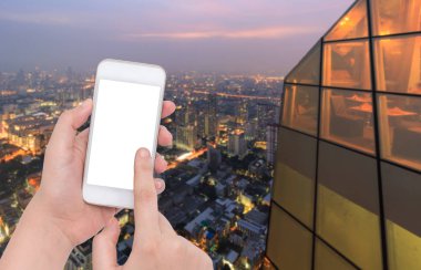 Bulanık Restoran Bangkok City gece arka plan üzerinde bir telefon tutarak el