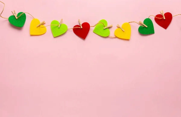 Corazones de colores se extienden con pinza de ropa sobre el fondo rosa pastel. San Valentín, día de la madre, tarjetas de felicitación de cumpleaños, invitación — Foto de Stock
