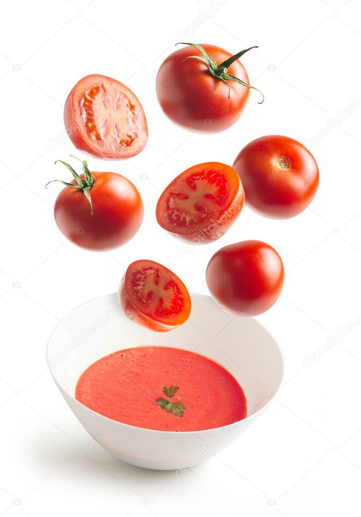 Fresh tomatoes flying, homemade tomato cream bowl, on white isolated background