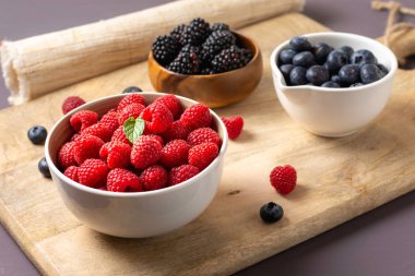 three bowls with wild berries, raspberry, blueberries, blackberries