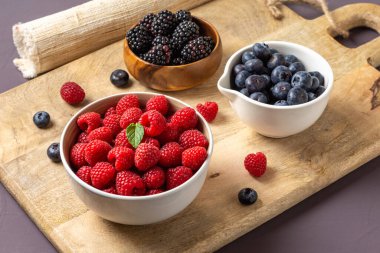 three bowls with wild berries, raspberry, blueberries, blackberries