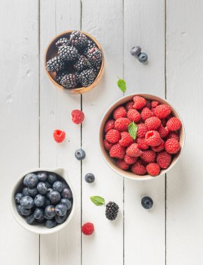 three bowls with wild berries, raspberry, blueberries, blackberries, zenith view