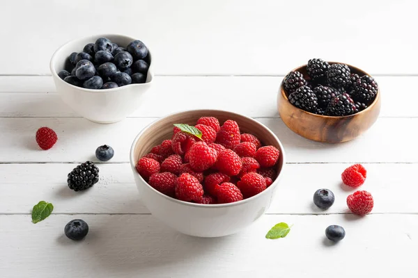 Three bowls with wild berries, raspberry, blueberries, blackberries, white background — ストック写真